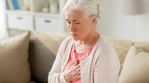 Frau fasst sich an das Herz