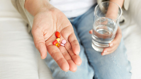 Frau nimmt Medikamente mit Wasser ein 