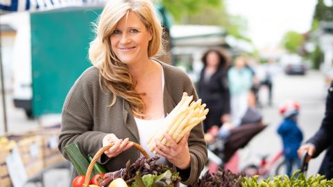Frau kauft auf dem Markt Spargel ein