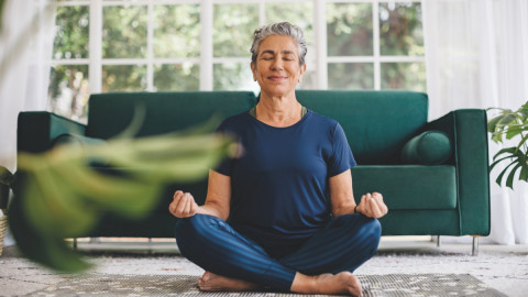 Frau macht zu Hause auf dem Boden eine Yoga übung. 